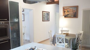 Une cuisine équipée d’une cuisinière à gaz, un coin repas avec une table et des chaises, et un tableau accroché au mur.