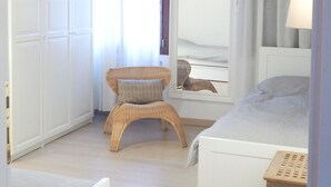 Une chambre à coucher avec un lit, une chaise, une petite table et un miroir.