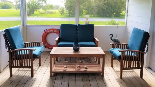 A porch with two wooden chairs and a table, a life preserver, and a bird sculpture. - Bird watching paradise! (Seadrift)