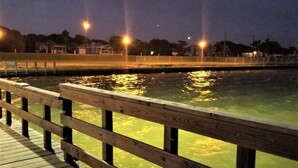 A wooden pier extending over calm water at night with streetlights in the background. - Bird watching paradise! (Seadrift)