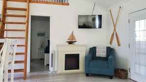 A living room with a wooden staircase, a fireplace, a television, and a blue sofa. - Bird watching paradise! (Seadrift)