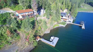 Une propriété au bord du lac, dotée d’un quai, d’une maison avec balcon et d’un bateau.