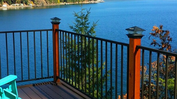 Une terrasse avec des chaises donnant sur un lac et des montagnes.