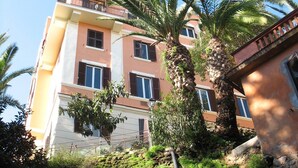 Un edificio de varios pisos con balcones, palmeras y un muro de piedra.