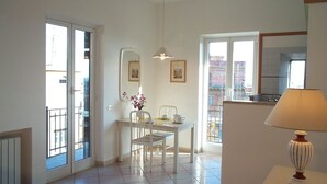 Una habitación luminosa y bien iluminada con comedor, una mesa y sillas, un jarrón de flores y una lámpara.