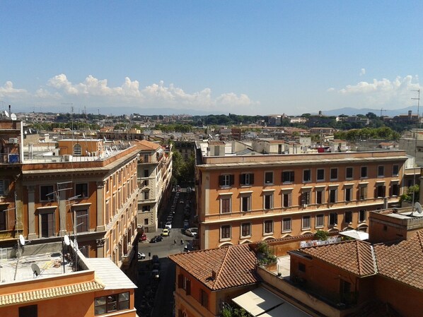 Une vue urbaine mettant en valeur un bâtiment imposant, doté d’une cour intérieure et bordé d’une rue.