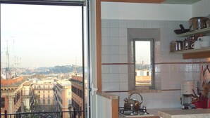 Una cocina con vistas a un paisaje urbano, una estufa a gas y una ventana que ofrece vistas de edificios.