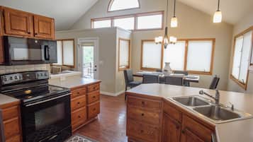 A kitchen with wooden cabinets, a black stove, and a large island with a sink.