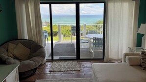 A room with a view of the ocean, a sliding glass door, a chair, a bed, and a small table. -  Gorgeous Gulf Front Condo on 30A! Back Porch Opens to Private Beach (Seacrest)