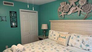 A bedroom with a bed, a nightstand, a lamp, and a wall decoration. -  Gorgeous Gulf Front Condo on 30A! Back Porch Opens to Private Beach (Seacrest)