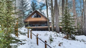 A wooden cabin with a balcony, surrounded by snow and trees. - Yellow Birch Lodge - Private Vacation Rental Home       (Eagle River)