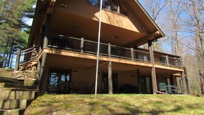 A two-story log cabin with a balcony, wooden deck, and a large window. - Yellow Birch Lodge - Private Vacation Rental Home       (Eagle River)
