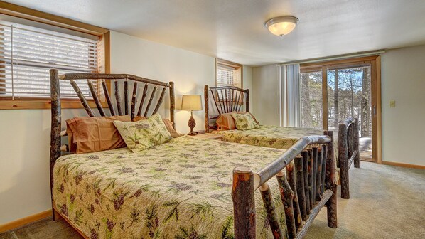 Un dormitorio con dos camas de madera, una ventana y una puerta que da al exterior.