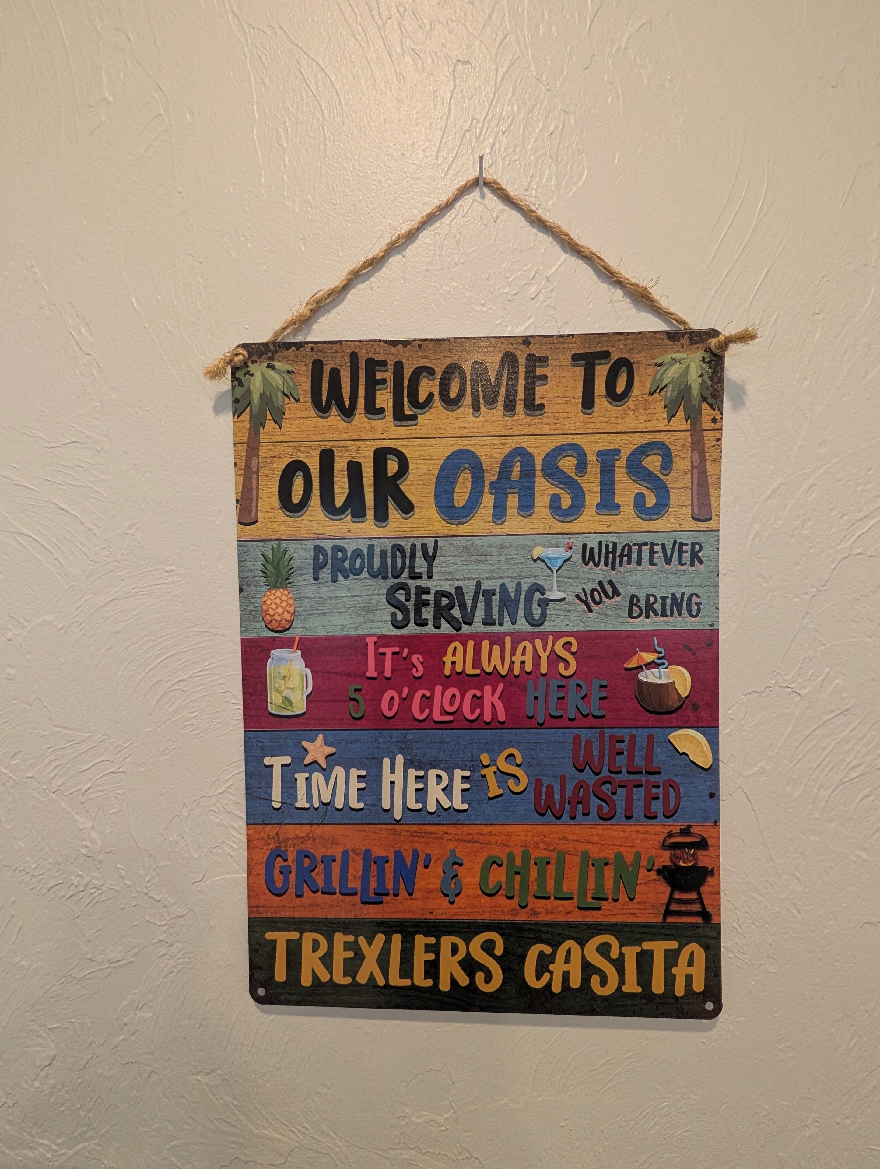 A colorful welcome sign with text and illustrations, hanging on a wall.