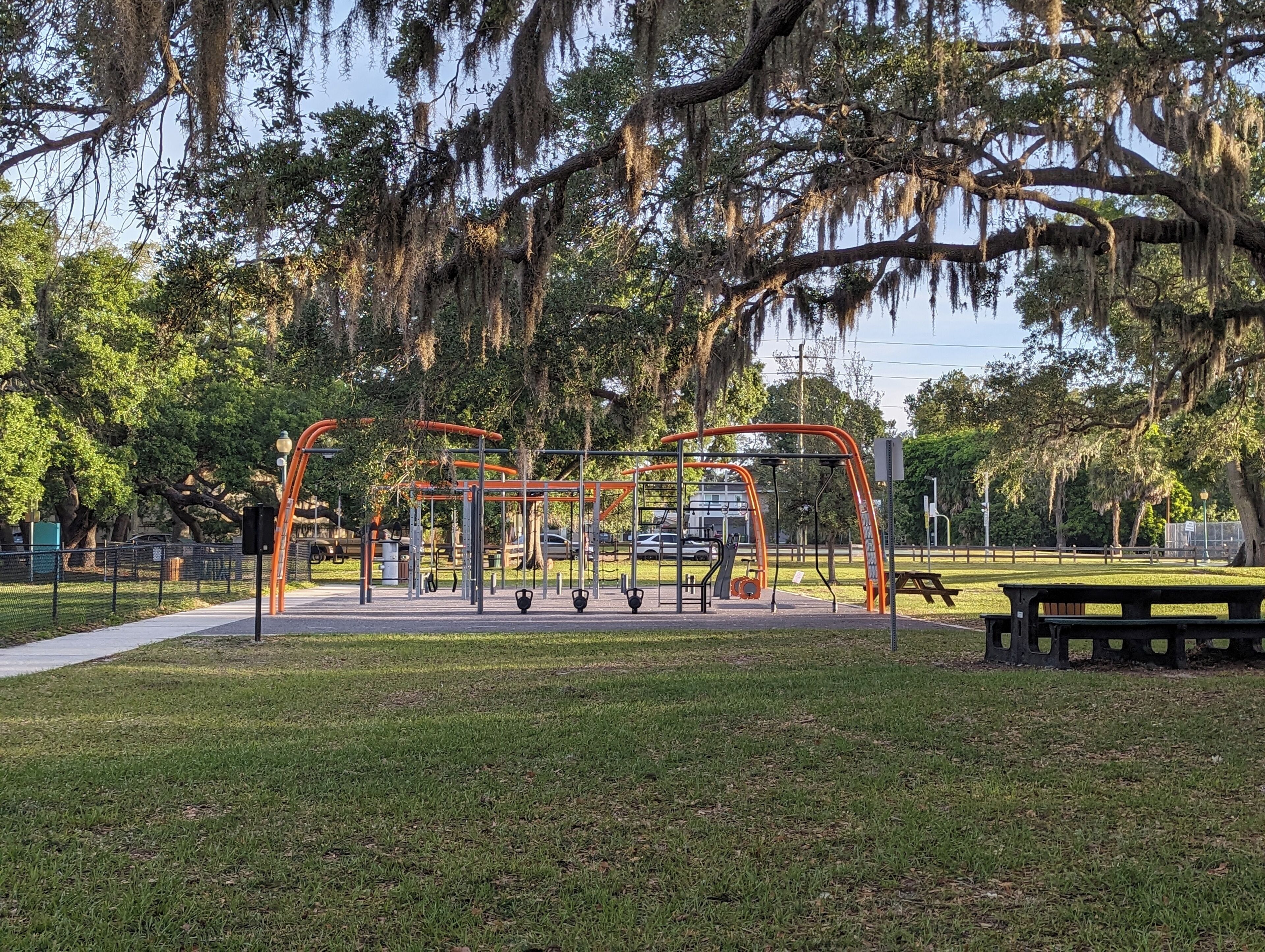 An outdoor park with exercise equipment, a picnic table, and a playground.