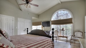 A bedroom with a bed, a ceiling fan, a large arched window, and a television on the wall. - Hattiway on Lake Allatoona Includes Private Covered Dock (Lake Allatoona)