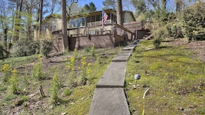 A house with a wooden deck and a flagpole, surrounded by trees and a grassy area. - Hattiway on Lake Allatoona Includes Private Covered Dock (Lake Allatoona)