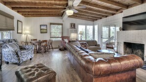 A spacious living room with a large leather sofa, a patterned armchair, and a dining area with a table and chairs. A fireplace is visible in the background. - Hattiway on Lake Allatoona Includes Private Covered Dock (Lake Allatoona)