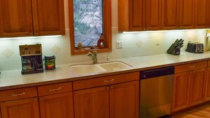 A kitchen with wooden cabinets, a built-in window, a coffee maker, a toaster, and a dishwasher. - Beautiful, pet friendly and at the foot of Saxon Mountain in Georgetown Colorado (Georgetown)