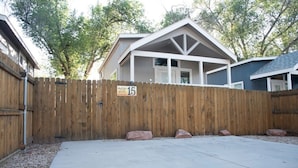 A residential property with a fenced backyard, a concrete patio, and a house with a gabled roof. - Pet-Friendly Moab Tiny Home Near Arches | Sleeps 6 | Private Porch | Desert View (Moab)