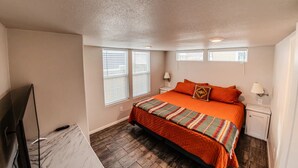 A bedroom with a bed, two bedside tables, a TV, and a window. - Pet-Friendly Moab Tiny Home Near Arches | Sleeps 6 | Private Porch | Desert View (Moab)