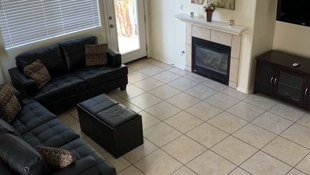 A living room with a sectional sofa, ottoman, fireplace, and a TV. - Vacation paradise (Las Vegas)