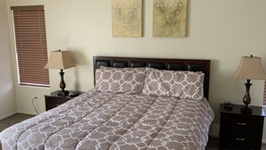 A bedroom with a bed, two nightstands, a ceiling fan, and two wall-mounted paintings. - Vacation paradise (Las Vegas)