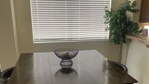 A dining table with a black wire basket in the center, flanked by two dark brown chairs. - Vacation paradise (Las Vegas)