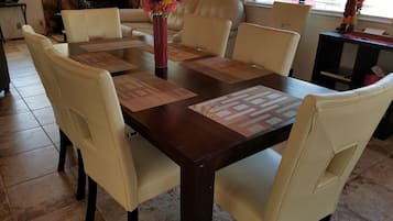 Ein Essbereich mit einem Holztisch, weißen Stühlen und einer Blumenvase.