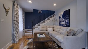 Una sala de estar con un sofá, una mesa de centro y una escalera.