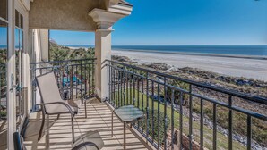 A balcony with a view of the beach, outdoor furniture, and a clear sky. - Direct Oceanfront Luxury Home, Large Private Pool and Spa, Elevator, Concierge! (Hilton Head Island)