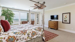 A bedroom with a large bed, a ceiling fan, a TV, a dresser, and a view of the ocean. - Direct Oceanfront Luxury Home, Large Private Pool and Spa, Elevator, Concierge! (Hilton Head Island)