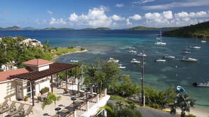 A coastal view with a marina, clear turquoise waters, and a building with outdoor seating. - Grande Bay Condo Beautiful Morning- 3 Bedroom - Wraparound Balcony- Views!! (St John)