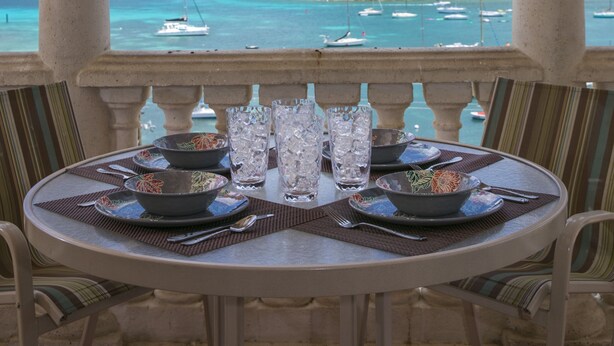 A table set for two with a view of the sea and boats. - Grande Bay Condo Beautiful Morning- 3 Bedroom - Wraparound Balcony- Views!! (St John)