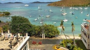 A coastal view with multiple boats on clear turquoise water, a sandy beach, and a hilly landscape in the background. - Grande Bay Condo Beautiful Morning- 3 Bedroom - Wraparound Balcony- Views!! (St John)