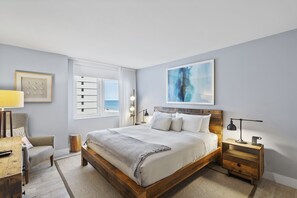 Une chambre à coucher avec un grand lit, des tables de chevet, une chaise, une lampe et une fenêtre avec des rideaux.