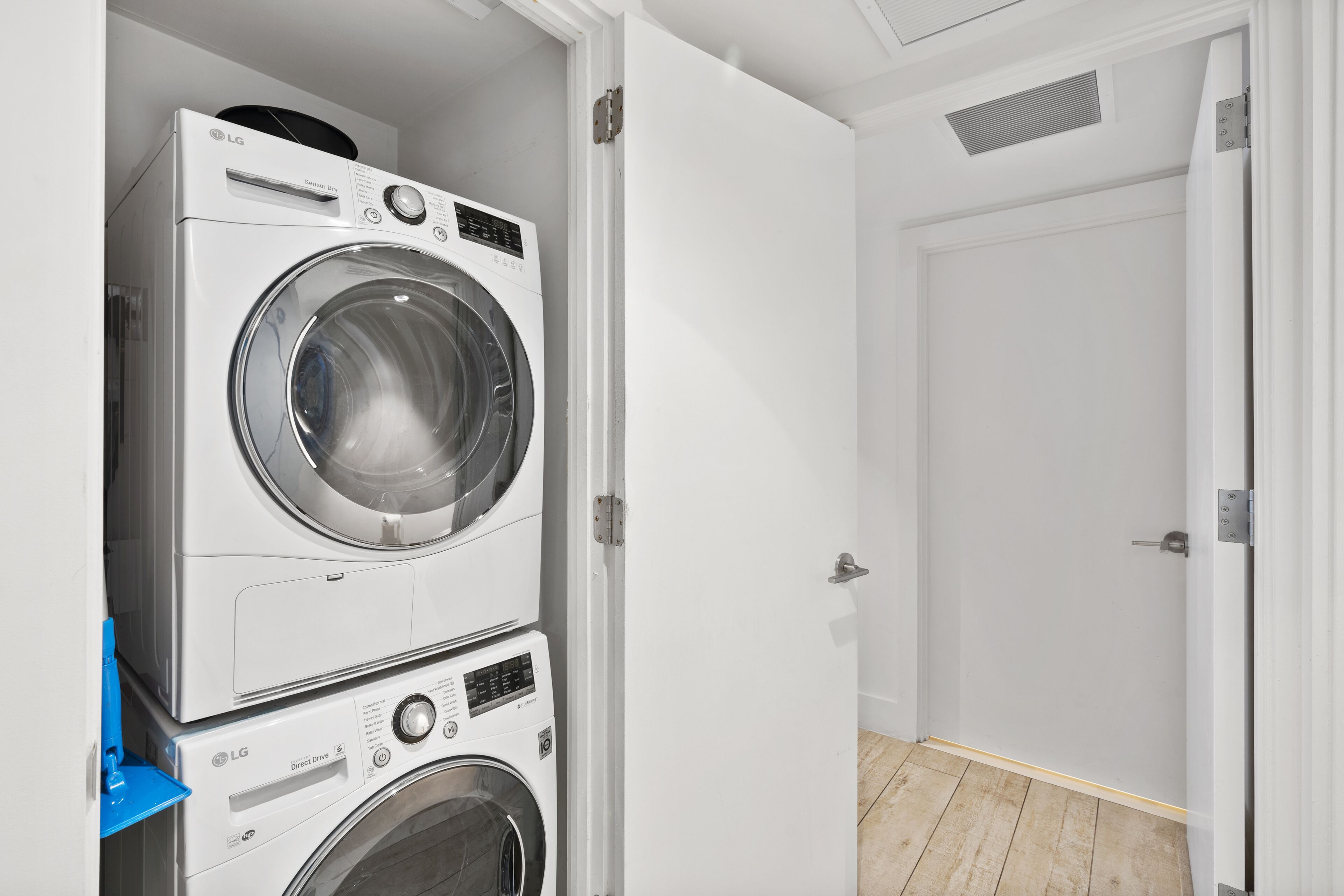 A laundry room with stacked washing machines and a closed door.