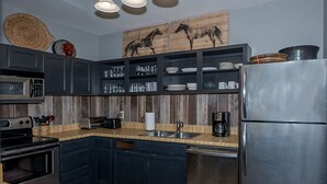 Una cocina moderna con armarios oscuros, un refrigerador de acero inoxidable y un protector contra salpicaduras de madera.