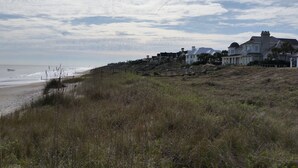 Propiedad costera con vista a la playa, una escalera que conduce a una casa y un primer plano con césped.