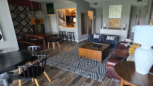 Una sala de estar moderna con comedor, una cocina al fondo y una alfombra estampada.