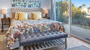 Une chambre avec un grand lit, un banc et une vue sur l’extérieur.