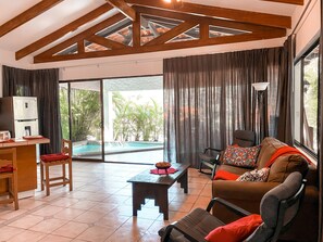 A spacious living area with a pool view, wooden beams, and a modern sofa.