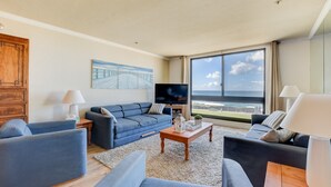 Een moderne woonkamer met een groot raam, een flatscreen televisie en een houten kast.