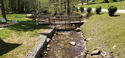 Rustic two-story cabin on creek with covered bridge and water wheel...