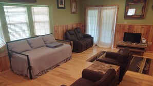 Una sala de estar acogedora con sofá, sillones y televisor.