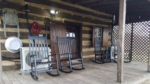Eine Veranda aus Holz mit Schaukelstühlen, einem Tisch und einem an der Wand befestigten Ventilator.