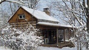 Eine Holzhütte mit Veranda, umgeben von schneebedeckten Bäumen.