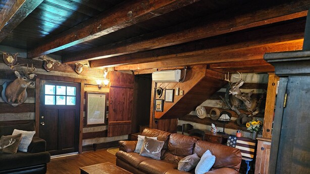 Ein rustikales Blockhaus-Interieur mit Ledersofa, Holzbalken und aufgehängten Tierköpfen.