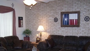 A living room with two dark leather sofas, a wooden coffee table, a lamp, and a wall with a Texas flag decoration.