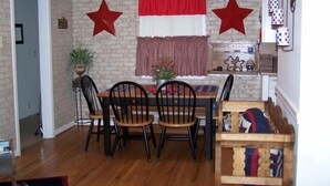 A dining area with a wooden table and chairs, a ceiling fan, and a brick wall.